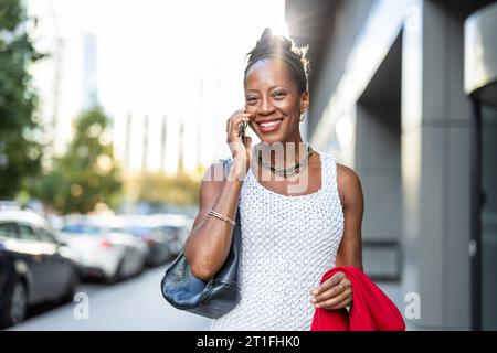 Porträt einer lächelnden Frau mit Handy in der Stadt Stockfoto