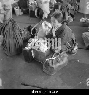 Die britische Wiederbesetzung von Hong Kong Eine ältere japanische Frau wartet gespannt am Hafen für den Transport, die Sie zu Stanley Camp, Hong Kong. Rund 3.000 japanische Zivilisten wurden von Kowloon nach Stanley Camp, das während des Krieges von der japanischen Besatzungsmacht als Internierungslager für Alliierte Zivilisten eingesetzt wurde verschoben. Stockfoto