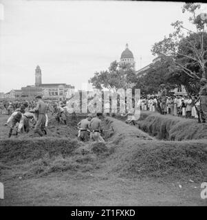 Die britische Wiederbesetzung von Singapur außerhalb der städtischen Gebäude in Singapur, Japanische Kriegsgefangene füllen in den Gräben, die Sie gezwungen hatte, die alliierten Kriegsgefangenen, die während des Krieges zu graben. Stockfoto