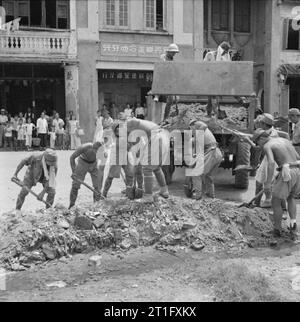 Die britische Wiederbesetzung von Singapur japanische Kriegsgefangene bei der Arbeit clearing Schutt von einer Straße in Singapur. Stockfoto