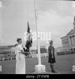 Die Japanische südlichen Armeen in Singapur, 1945 Herausgabe einer naval Bewertung bereitet die Union Jack nach Lord Louis Mountbatten, Supreme Allied Commander, Südostasien Hoist, lesen die Reihenfolge der Tag, der von der feierlichen Übergabe aller japanischen südlichen Armeen erzählt. Stockfoto