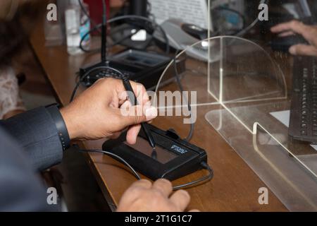 Linkshänder signieren sein Autogramm auf dem digitalen Pad während einer standesamtlichen Zeremonie im Rathaus. Stockfoto