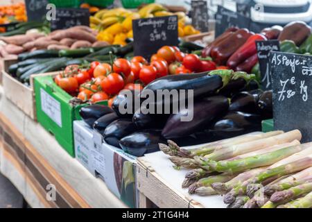 Spargel, Auberginen, rote Tomaten und anderes frisches Gemüse werden auf dem Markt im Freien in Arles, Provence, Südfrankreich, angeboten. Stockfoto