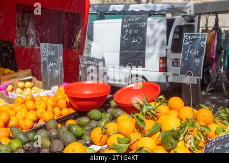 Orangen, Avocados, Birnen und Clementinen zum Verkauf auf dem samstags-Markt in Arles, Provence, Südfrankreich. Rote Plastikschalen im Vordergrund. Stockfoto