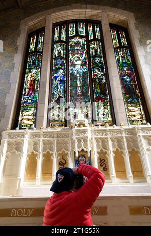 Fotograf, der ein Foto von einem Buntglasfenster in einer verlassenen Kirche macht Stockfoto