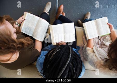 Drei Frauen sitzen auf einer Couch mit offenen Bibeln. Stockfoto