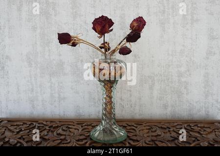 Getrocknete Rosen in einer Glasvase. Getrocknete Rosen auf dem Holztisch. Rosen in der Vase. Stockfoto