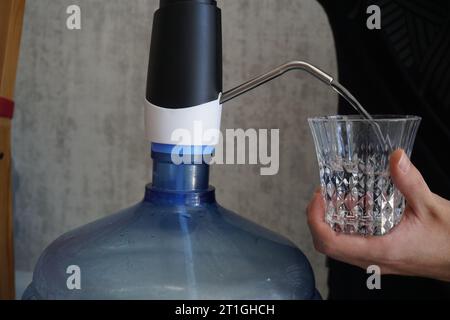 Eine Person, die Wasser füllt. Eine Person, die Wasser zum Trinken füllt. Eine Person, die eine Kanne mit Wasser füllt. Eine Person, die Wasser aus einem Wasserspender füllt. Stockfoto