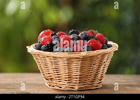 Korbschale mit verschiedenen frisch Reifen Beeren auf Holztisch im Freien Stockfoto