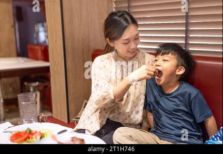 Glückliche Mutter füttert ihren Sohn im Restaurant Stockfoto