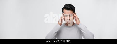 Hübscher asiatischer Mann mit Hand auf Kopf, Kopfschmerzen wegen Stress. Migräne leiden. Stockfoto