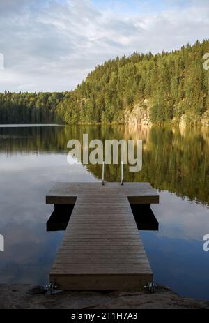 Holzpier auf einem See im Südlichen Konnevesi-Nationalpark, Finnland. Sommerlandschaft mit der Reflexion. Stockfoto