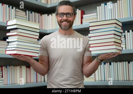 Lehrertag. Guter Lehrer. Tutor im Klassenzimmer. Mann Lehrer mit Büchern im Klassenzimmer. Wissens- und Bildungskonzept. Lustiger Lehrer hält viele Bücher Stockfoto