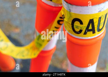 Gelbes Klebeband mit dem Wort „Achtung“ hängt an orangefarbenen und weißen Pollern in einer Bauzone in Vancouver, Kanada. Stockfoto