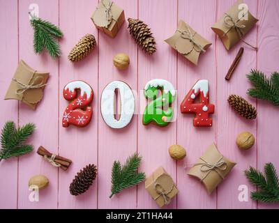 Die Zahlen sind Lebkuchen 2024 auf rosafarbenem Hintergrund. Schönes Flatlay aus natürlichen Materialien und Geschenken. Weihnachtshintergrund. Der Begriff des Minimalismus. Hochwertige Fotos Stockfoto