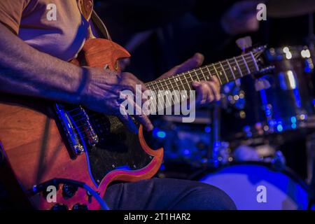 Nahaufnahme der Hände eines älteren Mannes, der Gitarre in einem Blues Jam in einem Londoner Pub mit Schlagzeug im Hintergrund spielt Stockfoto