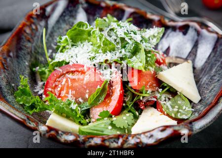 Salat mit Tomaten, Fetakäse, Salat und Petersilie in einer ungewöhnlichen Schüssel Seitenansicht Stockfoto