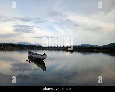 Traditionelles Holzboot auf dem Wasser des Lake Limboto, Gorontalo, Indonesien. Kleines hölzernes Ruderboot auf einem ruhigen See Stockfoto