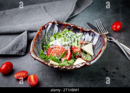 Salat mit Tomaten, Fetakäse, Salat und Petersilie in einer ungewöhnlichen Schüssel Seitenansicht Stockfoto