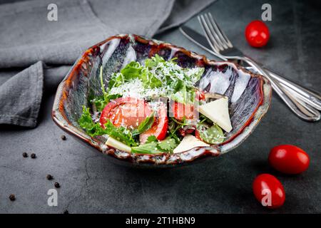 Salat mit Tomaten, Fetakäse, Salat und Petersilie in einer ungewöhnlichen Schüssel Seitenansicht Stockfoto