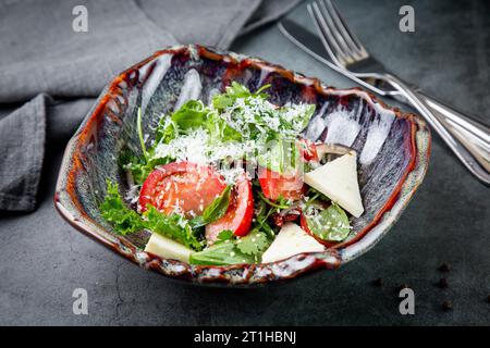 Salat mit Tomaten, Fetakäse, Salat und Petersilie in einer ungewöhnlichen Schüssel Seitenansicht Stockfoto