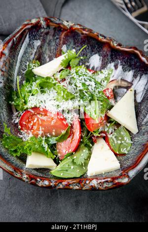 Salat mit Tomaten, Fetakäse, Salat und Petersilie in einer ungewöhnlichen Schüssel Seitenansicht Stockfoto