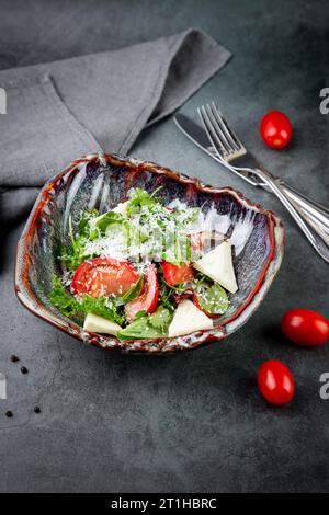 Salat mit Tomaten, Fetakäse, Salat und Petersilie in einer ungewöhnlichen Schüssel Seitenansicht Stockfoto