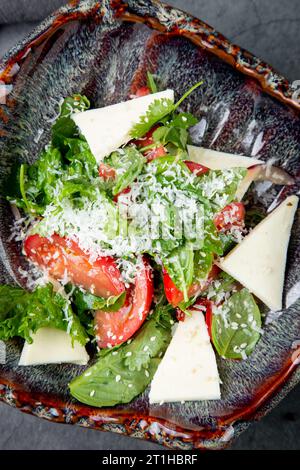 Salat mit Tomaten, Fetakäse, Salat und Petersilie in einer ungewöhnlichen Schüssel von oben Stockfoto