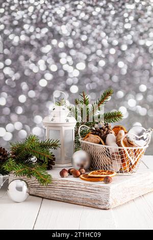 Neujahrs- und Weihnachtskomposition mit einer weißen Laterne, einem Korb mit Lebkuchen und getrockneten Orangenscheiben. Fichtenzweige. , Bokeh. Vertikale Ansicht Stockfoto