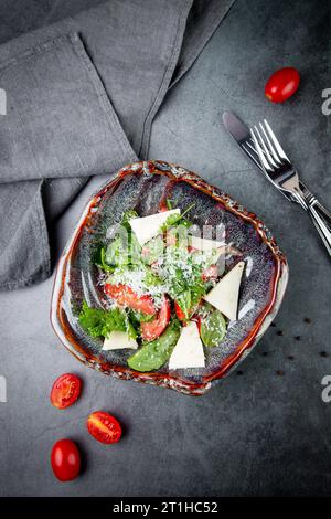 Salat mit Tomaten, Fetakäse, Salat und Petersilie in einer ungewöhnlichen Schüssel Seitenansicht Stockfoto