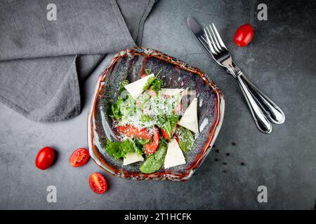 Salat mit Tomaten, Fetakäse, Salat und Petersilie in einer ungewöhnlichen Schüssel Seitenansicht Stockfoto