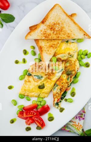 Frühstück mit Eiern und Gemüse mit Kirschtomaten und Brotscheiben auf einem weißen Teller mit Blick von oben Stockfoto