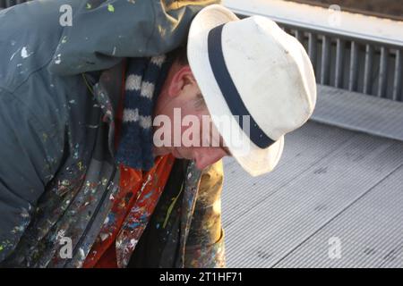 London, Großbritannien 14/Oktober/2023 Kaugummi Künstler kämpft gegen Time to Save Work die Millennium Bridge, die berühmte Fußgängerbrücke über die Themse, schließt zur Restaurierung. Der Verschluss verursacht Kontroversen, da Kunstwerke, die auf Kaugummi auf der Oberfläche der Brücke gemalt sind, entfernt werden. Kurz vor der Schließung verhandelt ein Vertreter der Bauunternehmer an der Brücke mit dem Künstler Ben Wilson. Wilson arbeitet bis in die letzte Minute daran, seine Miniatur-Kunst zu beschreiben, um sie vor den Hochdruckreinigern zu schützen. Vermerk: Roland Ravenhill/Alamy. Stockfoto