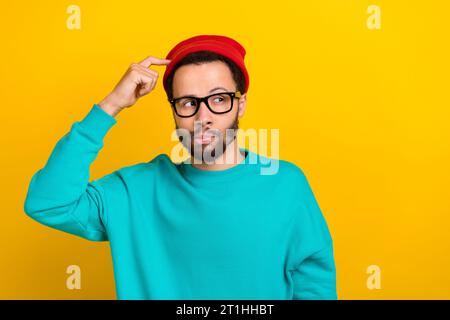 Porträt des cleveren Mannes mit Bart gekleidet türkisfarbenem Pullover Finger kratzenden Kopf Blick leerer Raum isoliert auf gelbem Hintergrund Stockfoto