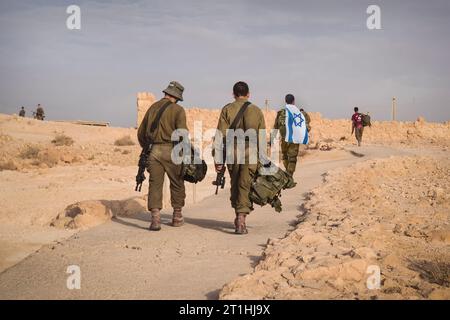 Rückaufnahme mehrerer Soldaten der israelischen Armee, die mit einer israelischen Nationalflagge unterwegs sind. Militärmann, der mit anderen Soldaten läuft. Kriegstaktische Übung. In Stockfoto