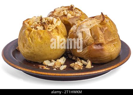 Gebackene Äpfel mit Nüssen auf einer braunen Keramikplatte, weißer Hintergrund Stockfoto