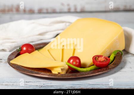 Gereifter Käse auf einer Kupferplatte. Organischer frischer Kuh Cheddar auf Holzhintergrund. Nahaufnahme Stockfoto