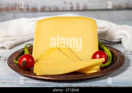 Gereifter Käse auf einer Kupferplatte. Organischer frischer Kuh Cheddar auf Holzhintergrund. Nahaufnahme Stockfoto