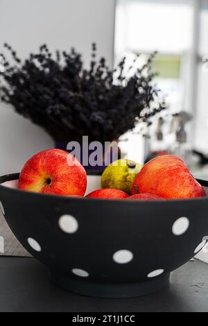 Rote Äpfel auf einer Keramikplatte, auf Lavendelhintergrund, Komposition Stockfoto