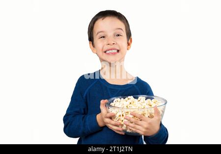 Dunkelhaariges kleines Kind, das Popcorn-Snack isst, isolierter weißer Hintergrund mit einem glücklichen Gesicht, das steht und lächelt, mit einem selbstbewussten Lächeln, das die Zähne zeigt Stockfoto