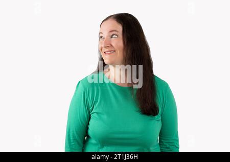 Frau trägt einen lässigen Pullover, der auf weißem Hintergrund steht und mit einem Lächeln auf dem Gesicht zur Seite schaut, natürlicher Ausdruck. Selbstbewusst lachen Stockfoto