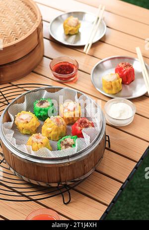 Buntes Siu Mai oder Shumai Siomai Dumpling Dimsum mit verschiedenen Belägen auf chinesischem Bambusdampfer Stockfoto