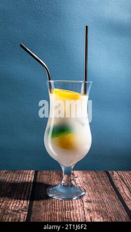 Ein weißer Cocktail auf einem Holztisch und blauem Hintergrund mit Kopierraum Stockfoto
