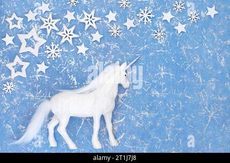 Weihnachtseinhorn magisches Ornament mit Schneeflocke und Sterndekorationen auf meliertem blauem Hintergrund. Festliche Fantasy Happy Holidays Design für Weihnachten... Stockfoto