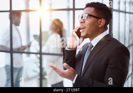 Nahaufnahme eines lächelnden jungen afrikaners, der im Büro per Handy spricht Stockfoto