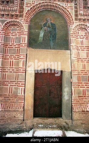 Tutana, Landkreis Arges, Rumänien, 2000. Außenansicht der St.. Athanasius-Kirche im Tutana-Kloster, ein historisches Denkmal aus dem 15. Jahrhundert. Ein Fresko des schutzheiligen über dem Eingang und die ursprüngliche Inschrift in Stein gemeißelt. Stockfoto
