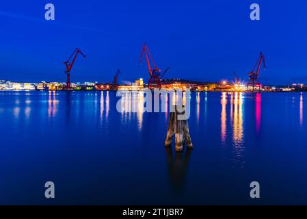 Blauer Abendhimmel über dem beleuchteten Göteborger Hafen mit Kränen und Maschinen. Stockfoto