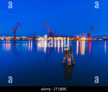 Blauer Abendhimmel über dem beleuchteten Göteborger Hafen mit Kränen und Maschinen. Stockfoto