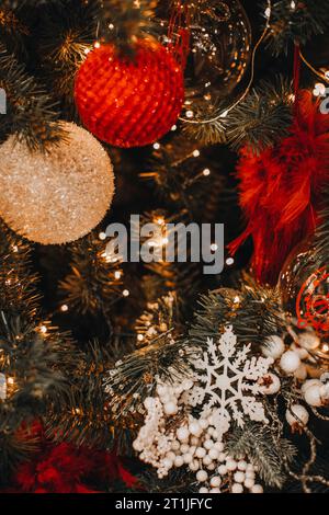 Goldene rote Weihnachtskugeln hängen am Weihnachtsbaum. Bokeh Girlande Magic Effect. Postkarte für festliche Winterferien Stockfoto