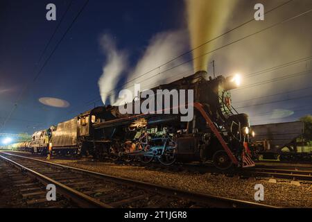 Alte funktionierende Dampflokomotive nachts auf der Bahn. Stockfoto